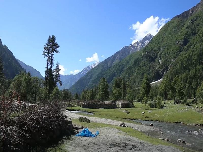 Scenic view of Sangla Valley with apple orchards and snow-capped mountains in the background.